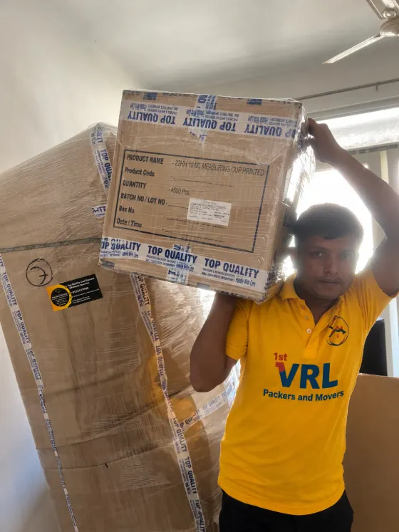 Packer carrying a wrapped carton during a VRL Packers and Movers job